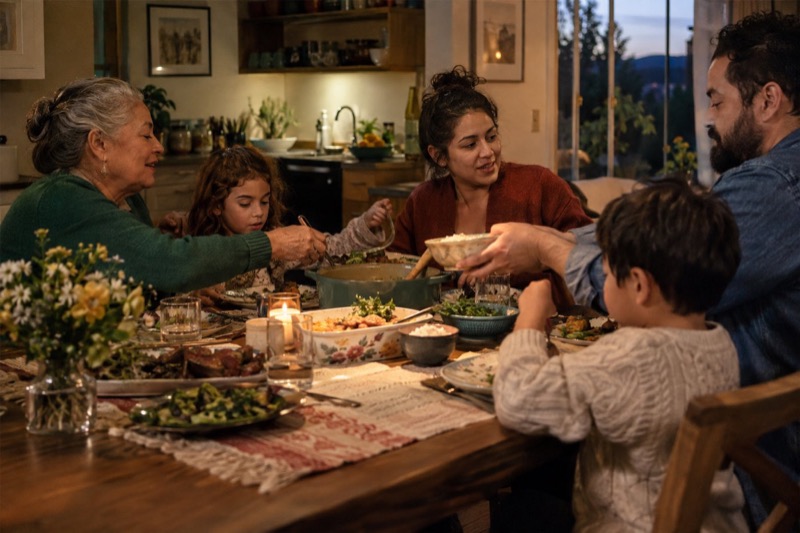 Three generations of a family passing dishes around a dinner table